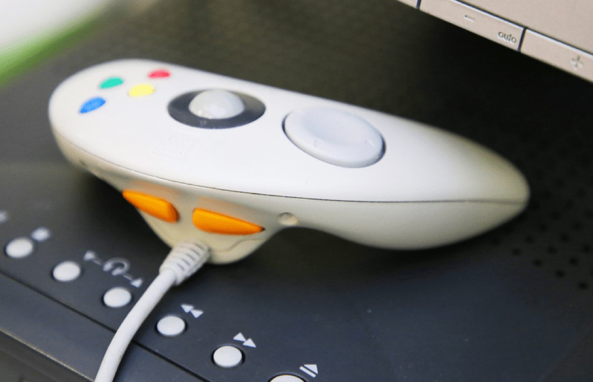 Gros plan sur la manette Applejack de l'Apple Pippin, avec sa boule de commande centrale et ses quatre boutons de couleur