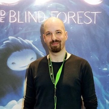 Thomas Mahler, fondateur de Moon Studios, devant une affiche d'Ori and the Blind Forest