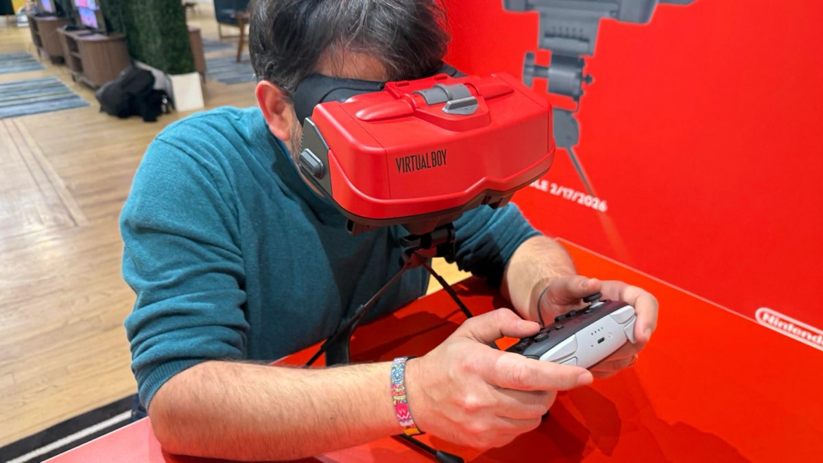 Una persona inclinada sobre el accesorio Virtual Boy para Switch en un stand de demostración de Nintendo, con el mando en las manos